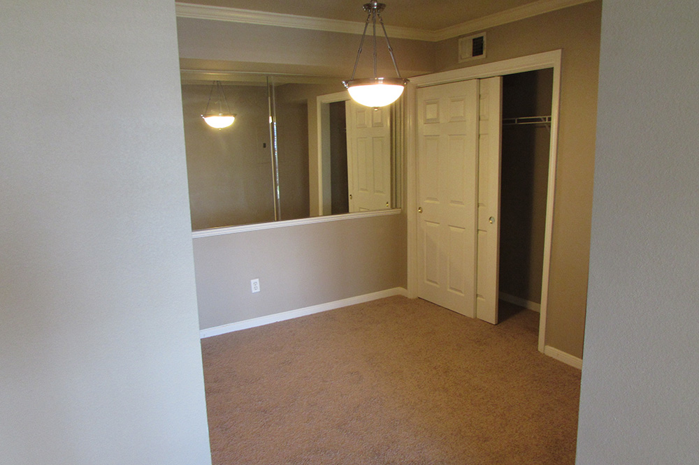 A look at a bedroom with a wall of mirrors and a double sliding closet door.