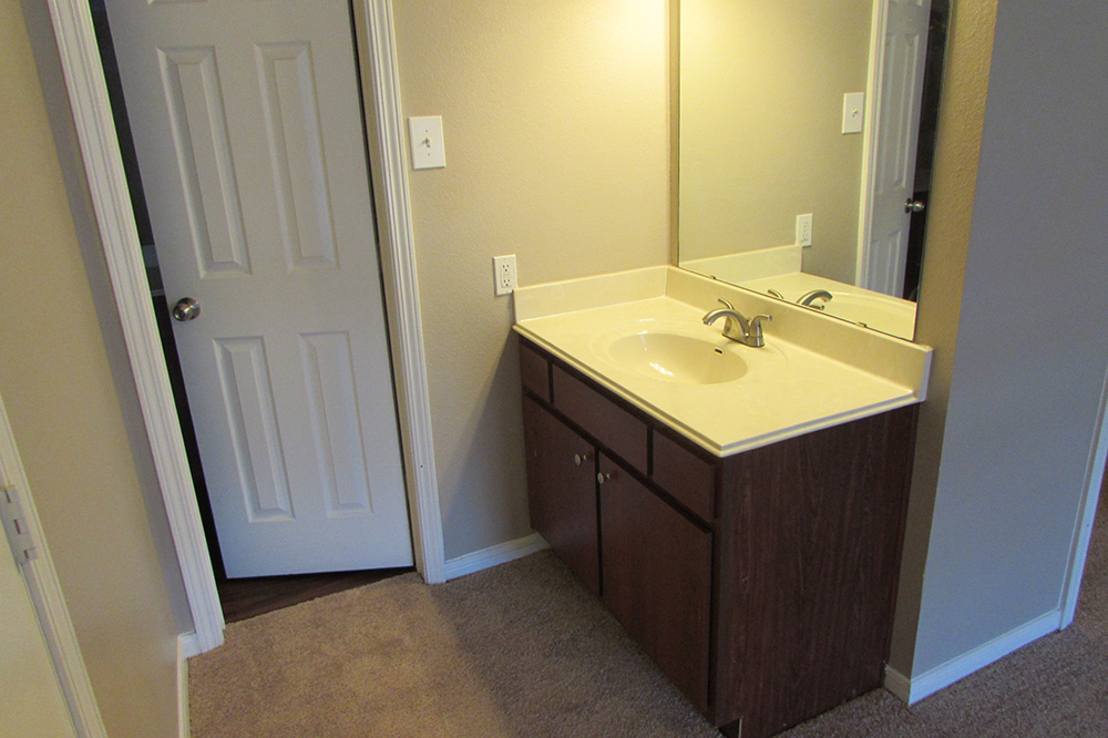 Sink and mirror with the entrance to a toilet in the master bedroom.